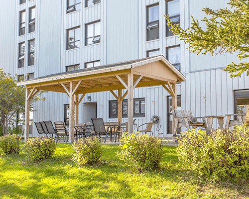 Viewing Lakeview Tower backyard where we can find picnic tables and chairs to sit and enjoy the lovely outdoor area under a wooden gazebo.